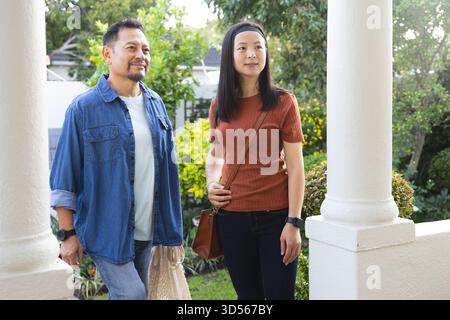 Reifes asiatisches Paar genießt gemeinsam einen Spaziergang im Freien, lächelt und blickt auf die Natur Stockfoto