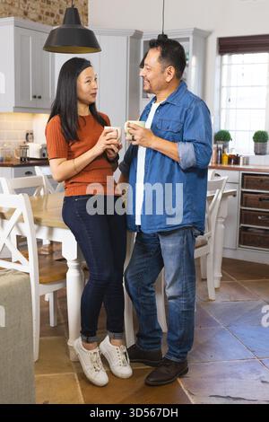 Ein älteres Ehepaar genießt gemeinsam Kaffee in einer gemütlichen Küche und unterhält sich warm Stockfoto