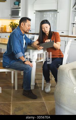 Reifes Ehepaar zu Hause diskutiert Pläne für die Verwendung eines digitalen Tablets in der Küche Stockfoto