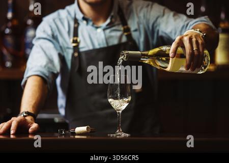 Sommeliermännchen gießt Weißwein in langstielige Weingläser. Stockfoto