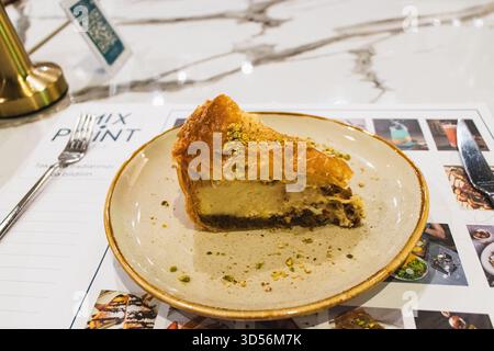 BAKU, ASERBAIDSCHAN. MISCHPUNKT. Eine Scheibe Käsekuchen mit Baklava und gemahlenen Pistazien garniert. Das ist ein kreatives Fusion Dessert, Combin Stockfoto