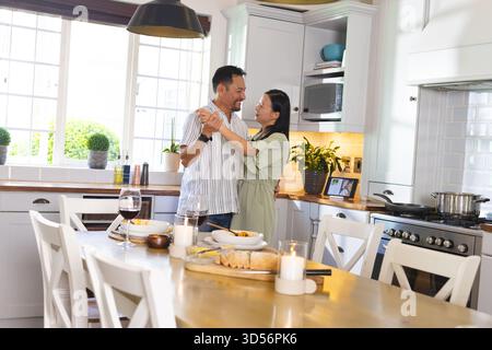 Asiatisches Paar tanzt zusammen in der Küche und genießt einen fröhlichen Moment zu Hause Stockfoto