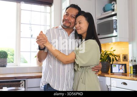 Reifes Paar tanzt glücklich in der Küche und genießt zarte Momente zusammen Stockfoto
