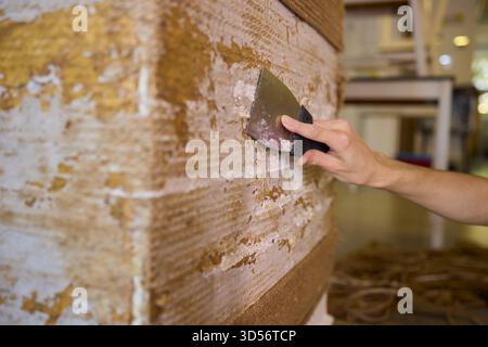 Auftragen von Putty auf eine Wandfläche mit einem Schaber-Werkzeug für eine glatte Oberfläche und Textur Stockfoto