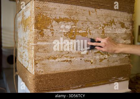 Auftragen von Putty auf eine Wandfläche mit einem Schaber-Werkzeug für eine glatte Oberfläche und Textur Stockfoto