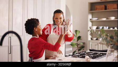 High Five, Backen und Mutter mit Kind in der Küche für weihnachtskekse, Dessert oder Kuchen zusammen. Happy, kochen und Mom unterrichten Jungen mit Stockfoto