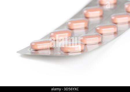 Packung mit rosafarbenen Kapseln in einer Reihe auf einer Folienunterlage angeordnet Stockfoto