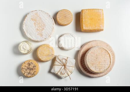 Verschiedene Käsesorten auf einer weißen Oberfläche mit verschiedenen Formen und Texturen Stockfoto