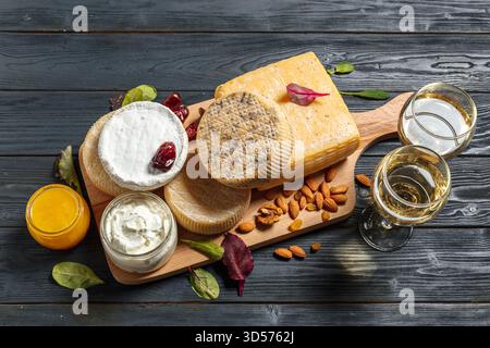 Käsebrett mit verschiedenen Käsesorten, Nüssen und Getränken auf Holztisch Stockfoto