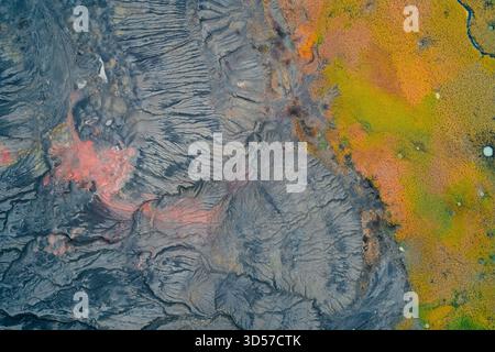 Abstrakter Hochwinkelschuss, der die starke Grenze zwischen grauem, stark erodiertem Industriegebiet mit rötlich-orangener saurer Tasche und lebhaftem Gelb- und grünen Herbstmoor erfasst Stockfoto