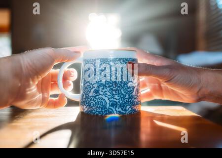 Hände halten Kaffeetasse mit Sonnenlicht am Morgen Stockfoto