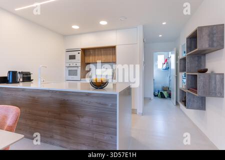 Stilvolle, moderne Küche mit eleganten Geräten, Holz- und weiß-Oberflächen und praktischer Grundausstattung einschließlich Insel und Stauraum. Stockfoto