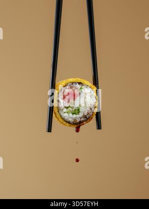 Gebackene Sushi-Rolle und Essstäbchen Stockfoto