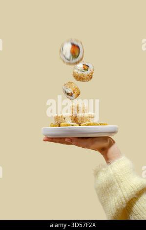 Fliegende Sushi-Rollen auf einem Teller in der Hand Stockfoto