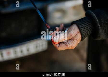 Mann, der den Ölstand im Fahrzeugmotor am Außenbereich überprüft Stockfoto