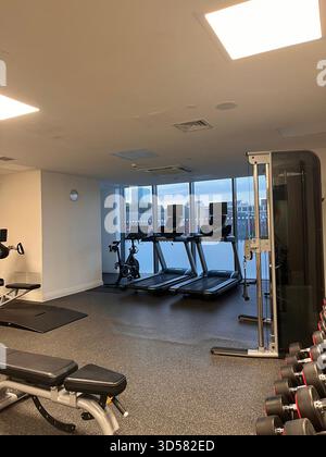 Eine saubere und moderne Inneneinrichtung des Fitnessstudios in Leeds, England, mit Laufbändern, Gewichten und großen Fenstern mit Blick auf die Stadt. Helle Beleuchtung und minimalistisch Stockfoto