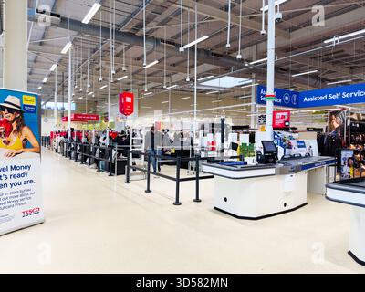 Manchester, Großbritannien - 30. September 2025: Kunden stehen bei der Selbstkasse in einem hellen Manchester Tesco an. Mitarbeiter helfen an den Schaltern einer überfüllten Superma Stockfoto