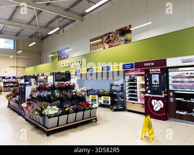 Manchester, Großbritannien - 30. September 2025: Helle Tesco Marktszene in Manchester mit Blumenausstellung, Essenstheke und Costa Coffee Kiosk. Stockfoto