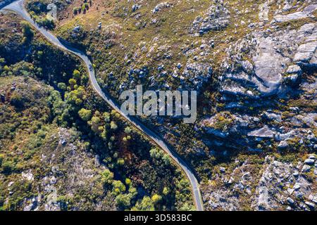 Eine einsame Asphaltstraße durch einen zerklüfteten und felsigen Bergpass. Stockfoto
