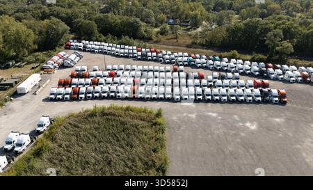 Viele Lkw parkten ordentlich auf einem überfüllten Grundstück unter klarem Himmel Stockfoto