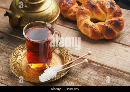 Türkischer schwarzer Tee. Eine Glasschale türkischer schwarzer Tee und knuspriger türkischer traditioneller Bagel auf altem Rustick-Hintergrund. Frühstücksgebäck-Konzept. Traditionelles türkisches Heißgetränk. Stockfoto