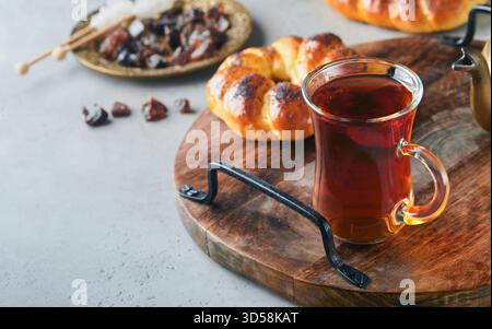 Türkischer schwarzer Tee. Eine Glasschale türkischer schwarzer Tee und knuspriger türkischer traditioneller Bagel auf grauem Betontischhintergrund. Frühstücksgebäck-Konzept. Traditionelles türkisches Heißgetränk. Stockfoto