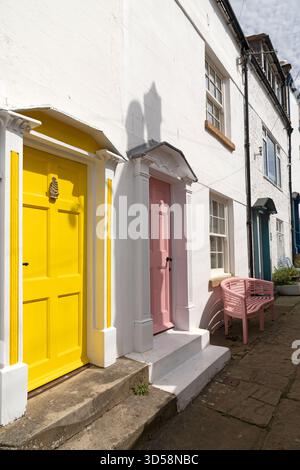 Farbenfrohe Eingangstüren in Robin Hood's Bay in North Yorkshire, England. Sie sind auf weiß gestrichenen Häusern. Stockfoto