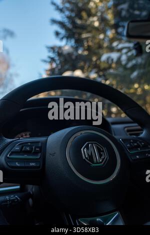 Issyk-Kul, Kirgisistan - 13. Dezember 2024: Vertikale Nahaufnahme des MG-Emblems und der Bedienelemente am Lederlenkrad mit weichem Fokus Stockfoto