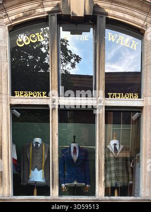 Eine stilvolle Schneiderei in Hull, England, zeigt Schaufensterpuppen in maßgeschneiderten Anzügen hinter einem reflektierenden Glasfenster. Der Klassiker des Shops PR Stockfoto