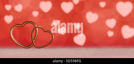 Zwei ineinandergreifende herzförmige Ringe auf einer Oberfläche mit einem verschwommenen herzgefüllten roten Hintergrund zum Valentinstag. 3D-Rendering Stockfoto