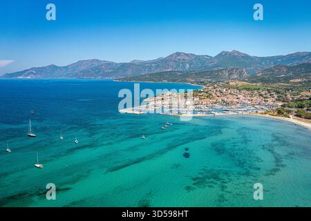 Eine lebendige Küstenstadt an einer Mittelmeerküste, mit einem geschäftigen Yachthafen, Sandstrand und türkisfarbenem Wasser. Korsika, Frankreich Stockfoto
