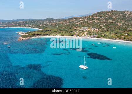 Helles türkisfarbenes Wasser trifft auf einen weißen Sandstrand, mit einer einsamen Segelyacht vor der Küste, Korsika, Frankreich Stockfoto