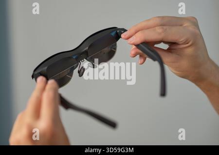 Nahaufnahme der Hände, die eine SMART AR-Brille halten. Konzept von tragbaren Technologien, Augmented-Reality-Geräten, Innovation, digitalem Lifestyle und moderner Technologie. Stockfoto
