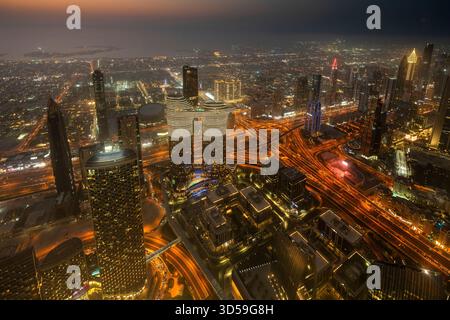 Ein atemberaubender nächtlicher Blick auf Abu Dhabi City von einem der höchsten Türme aus mit glitzernden Wolkenkratzern, beleuchteten Straßen und Reflexionen Stockfoto