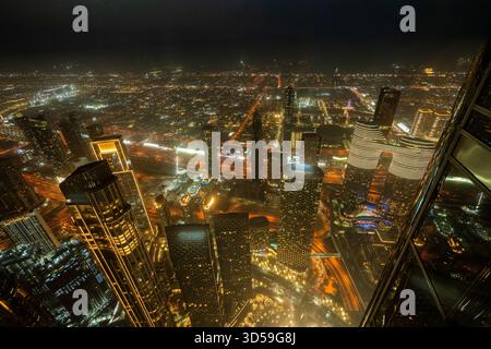 Ein atemberaubender nächtlicher Blick auf Abu Dhabi City von einem der höchsten Türme aus mit glitzernden Wolkenkratzern, beleuchteten Straßen und Reflexionen Stockfoto