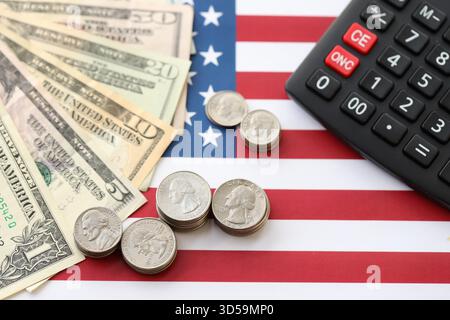 US-Dollar-Geldscheine und Taschenrechner auf amerikanischer Flagge Nahaufnahme. Geldinvestitionskonzept und Steuerzahlung Stockfoto