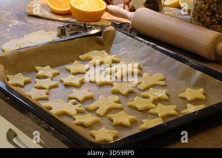Weihnachtsplätzchenteig, Gewürze und Keksschneider auf einem Küchentisch. Stockfoto