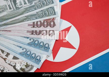 Nordkoreaner gewannen Geldscheine in großer Höhe lügen auf der Flagge der Volksrepublik Korea aus nächster Nähe. Finanz- und Bankkonzept Stockfoto