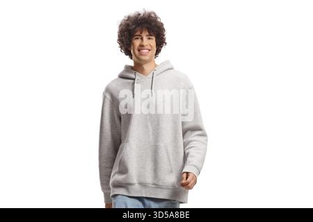 Ein Typ mit lockigen Haaren in einem grauen Hoodie und Jeans, der auf die Kamera zugeht, isoliert auf weißem Hintergrund Stockfoto