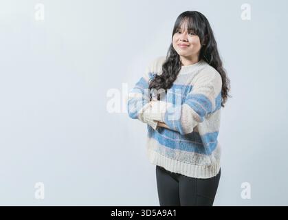 Porträt einer schönen und lächelnden asiatischen Frau auf isoliertem Hintergrund. Junge asiatische Frau mit gekreuzten Armen isoliert Stockfoto