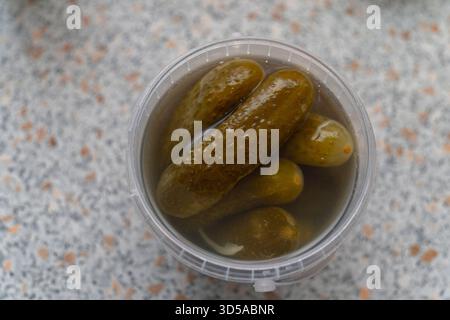 Eingelegte Gurken in Salzlake in einem Kunststoffbehälter Stockfoto