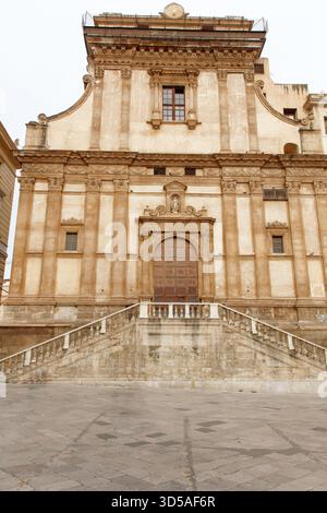 Eine große, sonnendurchflutete Kirchenfassade mit einem gemeißelten Marmoreingang, Säulen und einem Kreuz auf einem barocken Eingang. Ideal für Architektur, Geschichte, Stockfoto
