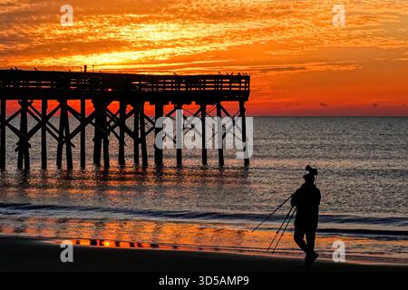 Isle Of Palms, Usa. November 2025. Ein Fotograf, der am 14. November 2025 bei Sonnenaufgang über dem Atlantik an einem bewölkten Morgen am Front Beach in Isle of Palms, South Carolina, eine Silhouette zeigt. Quelle: Richard Ellis/Richard Ellis/Alamy Live News Stockfoto