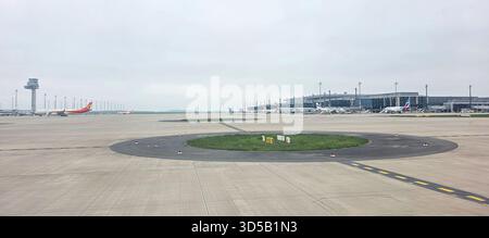 Doloman, Türkei - 25. April 2025: Flugzeuge werden am Flughafenterminal mit Start- und Landebahn und Kontrollturm im Hintergrund geparkt. Stockfoto