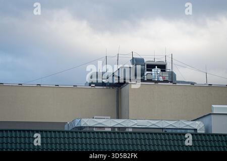 Auf dem Dach befindet sich ein kompaktes Lüftungssystem mit gefalteten Kanälen und Metallgehäusen, die ordentliche Baugruppe sieht gewartet und stabil aus, während sich die Luft leise bewegt Stockfoto