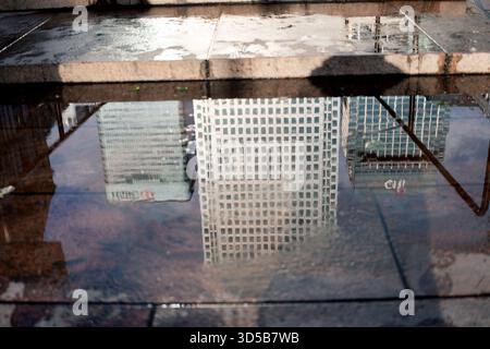 Ein Spiegelbild der Gebäude des kanarischen Kais spiegelt sich in einer Pfütze im kanarischen Kai wider. Stockfoto
