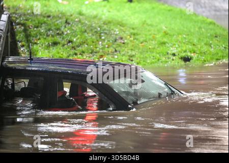 Green Road, Birmingham, 14. November 2025 - Ein Geländewagen wurde aufgegeben, nachdem der Fahrer am Freitagabend das Risiko hatte, einen überfluteten ford in der Hall Green Gegend von Birmingham zu befahren. Zertrümmerte Fenster waren zu sehen, was darauf hindeutet, dass die Insassen die Türen aufgrund des Wasserstroms nicht öffnen konnten. Am Abend hatte die Straße ein Feuerwehrkordonband, um die Fahrer davon abzuhalten, ihr Leben zu riskieren. Polizeiband wurde hinzugefügt, aber es sind keine Polizisten vor Ort. Das Fahrzeug ist unter einer Fußgängerbrücke verkeilt und verhindert, dass es stromabwärts schwimmt. Quelle: British News und Media/Alamy Live News Stockfoto