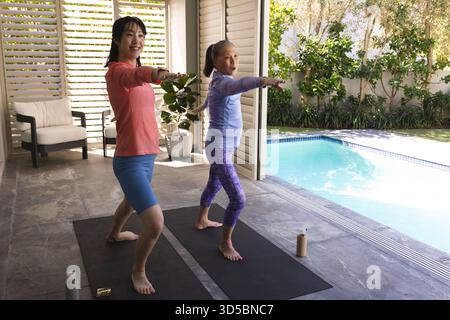 Zwei Frauen üben Yoga am Pool und genießen Sport und Entspannung im Freien. Fitness, Wellness, Meditation, Balance, Flexibilität, zen Stockfoto
