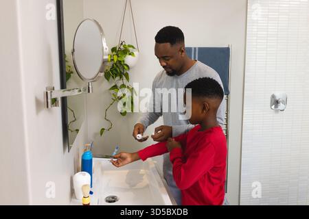 Vater und Sohn putzten im Badezimmer die Zähne zusammen, kleben und lächeln Stockfoto