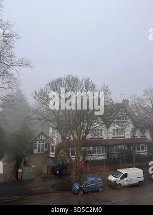 Nebelige Morgenszene mit traditionellen Backsteinhäusern und geparkten Autos in einer ruhigen Wohnstraße im dichten Nebel in Hull, England. Stockfoto